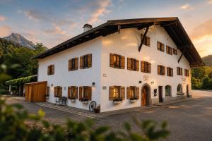 a large white building with windows and a sunset at Chalet Ferienwohnung zwischen Berchtesgaden und Ramsau in Bischofswiesen