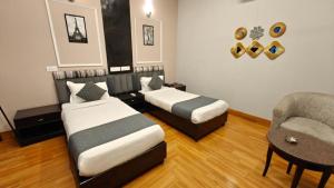 a hotel room with two beds and a chair at Pallavi West in Panchkula