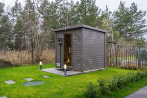 a small grey shed in a yard with a fence at Casa CaVi Bergheider See in Buschmühle