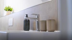 a bathroom sink with a faucet and two cups at Casa CaVi Bergheider See in Buschmühle