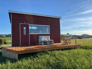 a tiny house with a deck in a field at TinyHouse pod Tatrami in Nižná Šuňava