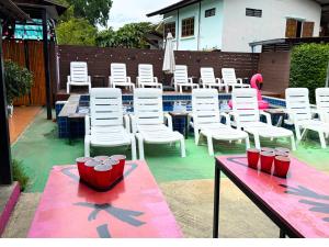 a group of white chairs and tables next to a pool at K-Bunk Hostel Pai Walking Street in Pai