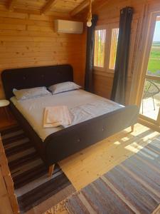 a bed in a wooden room with a window at Mar a Lago Glamping23 in Douăzeci şi Trei August