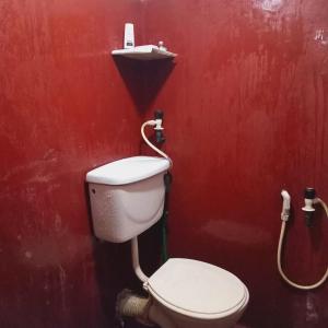 a bathroom with a toilet and a red wall at Hiru's Place in Gandara East