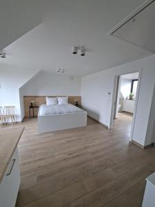 a white bedroom with a white bed and wooden floors at B&B El Bayo in Ravels +45 photos