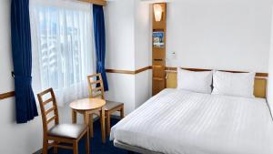 a bedroom with a bed and a table and chairs at Toyoko Inn Maebashi Ekimae in Maebashi