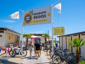 a group of people walking past a sign for a bicycle beach at Hotel Holland in Rimini