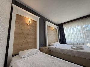 two beds in a hotel room with two windows at Özsoy Otel in Akçay