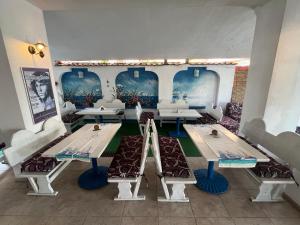 a room with tables and couches and paintings on the walls at Hotel NEMO in Kiten