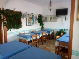 un restaurant avec des tables et des chaises bleues et une télévision dans l'établissement Pensione Aurora, à Imperia