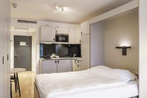 a small bedroom with a bed and a kitchen at Story Living Lidingö in Stockholm