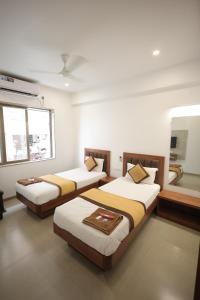 a room with three beds and a mirror at Hotel Rangoli Dharampur in Dharampur +25 photos