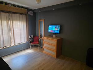 a bedroom with a television on a dresser with a chair at Slice of life in Qiryat Motzkin +1 photo