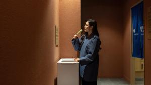a woman standing in a room with a toothbrush in her mouth at Anook Hotel & Spa Bucheon Sangdong in Bucheon