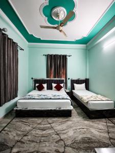 a bedroom with two beds and a ceiling fan at Bhagirathi Residency in Rishīkesh