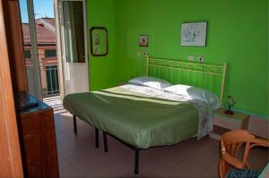 a green bedroom with a bed in front of a window at Hotel Villa Morgana in Viareggio
