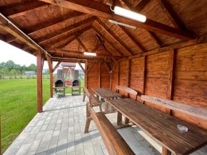a wooden pavilion with wooden benches in a field at Agroturystyka Ostoja Wilków II in Wilków