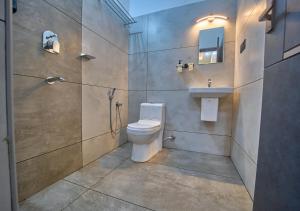 a bathroom with a toilet and a sink and a shower at De Waves Varkala by VOYE HOMES - Just 1 Km from Varkala Cliff and Beach in Varkala