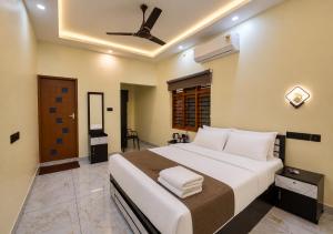 a bedroom with a large bed with a ceiling fan at De Waves Varkala by VOYE HOMES - Just 1 Km from Varkala Cliff and Beach in Varkala