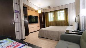 a hotel room with a bed and a television at Beckham Motel in Luzhu
