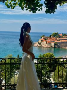 a woman in a wedding dress looking at the ocean at Villa Milan in Sveti Stefan +99 photos