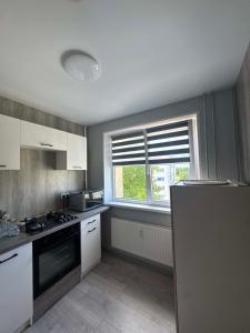 a kitchen with white cabinets and a window at Geri apartamentai in Naujoji Akmenė