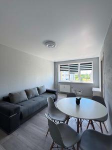 a living room with a couch and a table and chairs at Geri apartamentai in Naujoji Akmenė