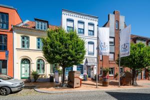 eine Häuserreihe in einer Stadtstraße mit Flaggen in der Unterkunft Nordsee-Hotel Hinrichsen in Husum
