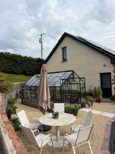 a patio with a table and chairs and a greenhouse at The Loft in Clonmore
