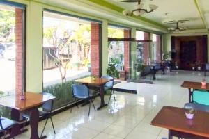 a restaurant with tables and chairs and a large window at Urbanview Hotel Grand Palem near Alun Alun Batu in Songgoriti
