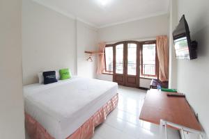 a bedroom with a bed and a flat screen tv at Urbanview Hotel Grand Palem near Alun Alun Batu in Songgoriti