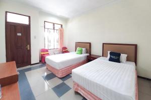 a hotel room with two beds and a window at Urbanview Hotel Grand Palem near Alun Alun Batu in Songgoriti