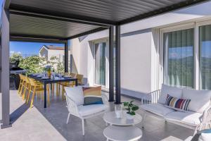a patio with white chairs and a table with a dining room at Villa Alice in Montecosaro