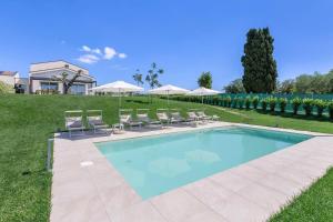 a swimming pool with chairs and umbrellas at Villa Alice in Montecosaro