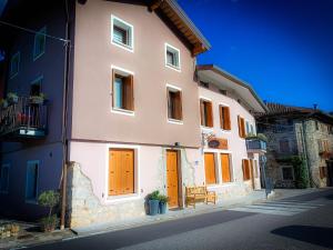 a building with orange doors and a bench on a street at Casa Vacanze Borc dai Cucs in Faedis