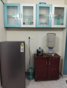 a kitchen with blue cabinets and a refrigerator at Venya Vihar Vizag MVP AC Deluxe 1 BHK Studio Apartment in Visakhapatnam