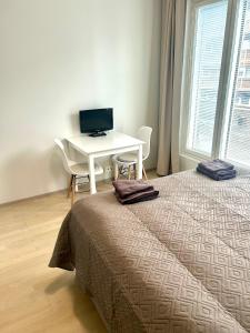 a bedroom with a bed and a desk with a computer at Syke Apartment Jyväskylä in Jyväskylä