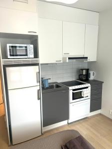a kitchen with a white refrigerator and a sink at Syke Apartment Jyväskylä in Jyväskylä