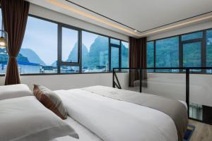 two beds in a room with a large window at Ruqi Hotel in Yangshuo +38 photos