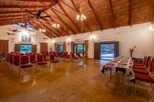 a banquet hall with red chairs and tables in a room at Ashvana Resort in Nidigere