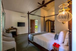 a bedroom with a canopy bed and a tv at Ashvana Resort in Nidigere