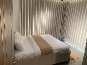 a bedroom with a bed and a window with curtains at Apex Hills تلال القمة in Dār Sawdāʼ