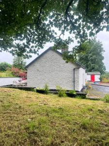 a white building with a red roof on a field at Campbell's Cottage in Blackwatertown