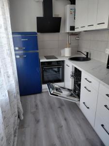 a kitchen with white cabinets and a blue refrigerator at SV Apartment in Jõhvi