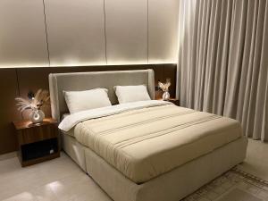 a bedroom with a large bed with white sheets at أواسِيس Oasis Stay in Al Muḩassin