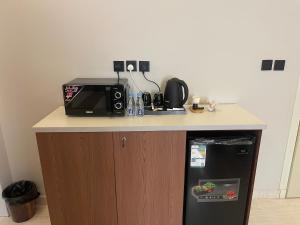 a kitchen counter with a microwave and a refrigerator at أواسِيس Oasis Stay in Al Muḩassin