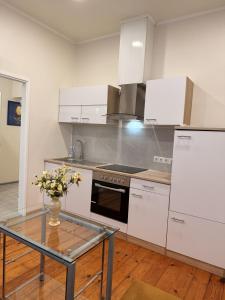 a kitchen with white cabinets and a glass table at LIINA apartment in Vahtseliina