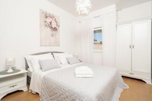 a white bedroom with a bed and a window at Apartments Doris in Zadar
