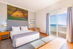 a bedroom with a bed and a large window at Hotel Maritur - Adults Only by Pierre & Vacances in Albufeira