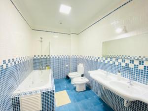 a blue and white bathroom with a tub and a toilet at Aloha Burgau Guesthouse in Burgau